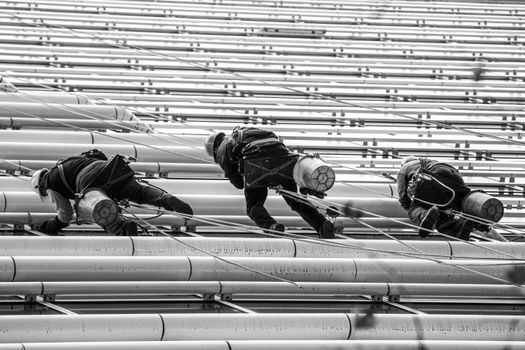 Monochrome image of workers climbing a steel structure showcasing urban life and industry in Buenos Aires.