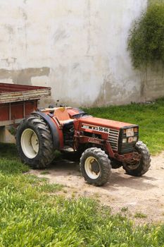 A classic red tractor parked outdoors on a sunny day in a farm setting.